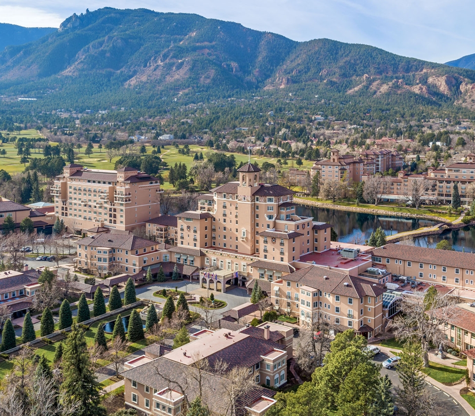 Aerial view of resort hotel on sunny morning with mountains and blue skies