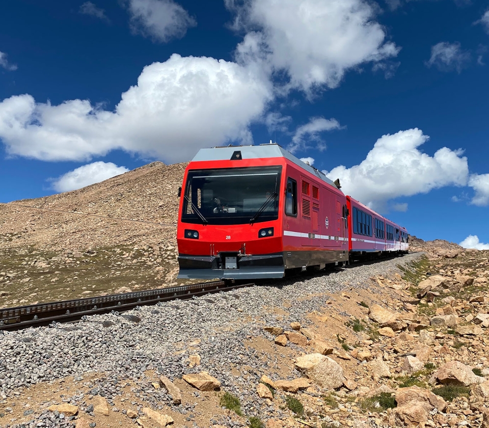 Red train on track coming down mountain
