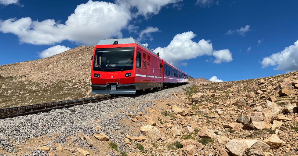 Red train on track coming down mountain