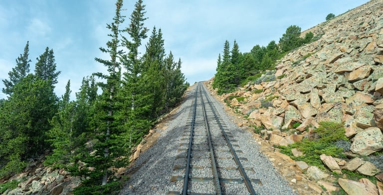 Empty train tracks and green trees on a mountain