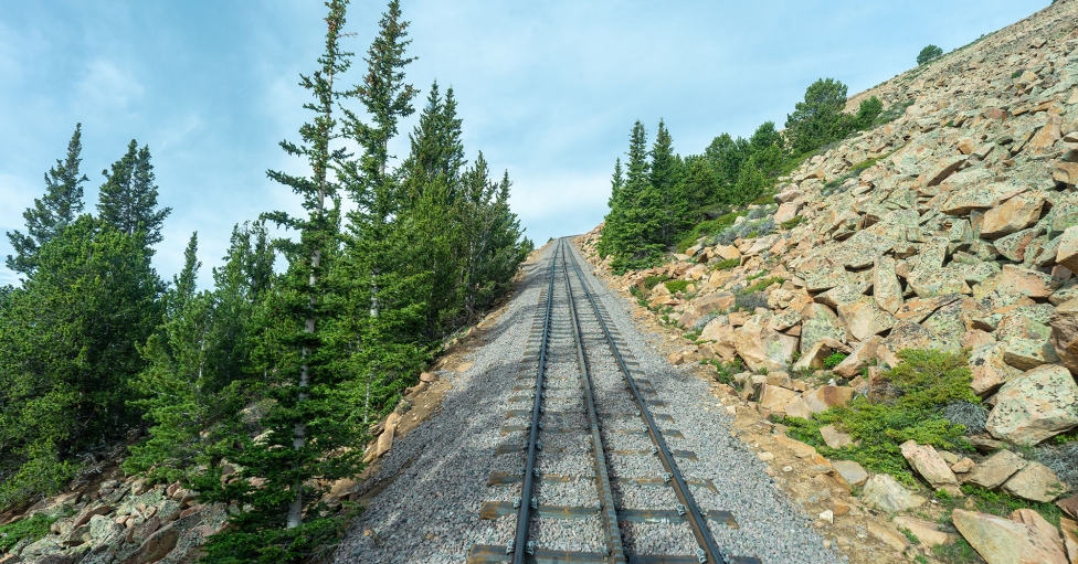 Empty train tracks and green trees on a mountain