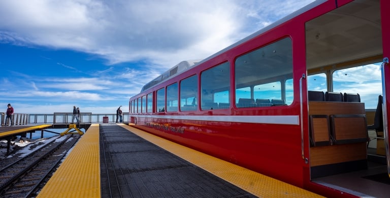 Couple taking selfie on mountain next to red train on tracks