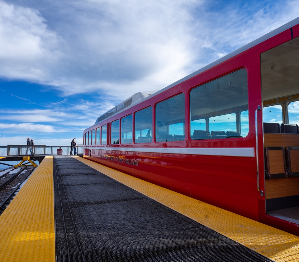 Couple taking selfie on mountain next to red train on tracks