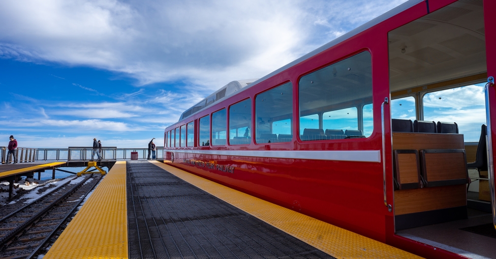 Couple taking selfie on mountain next to red train on tracks