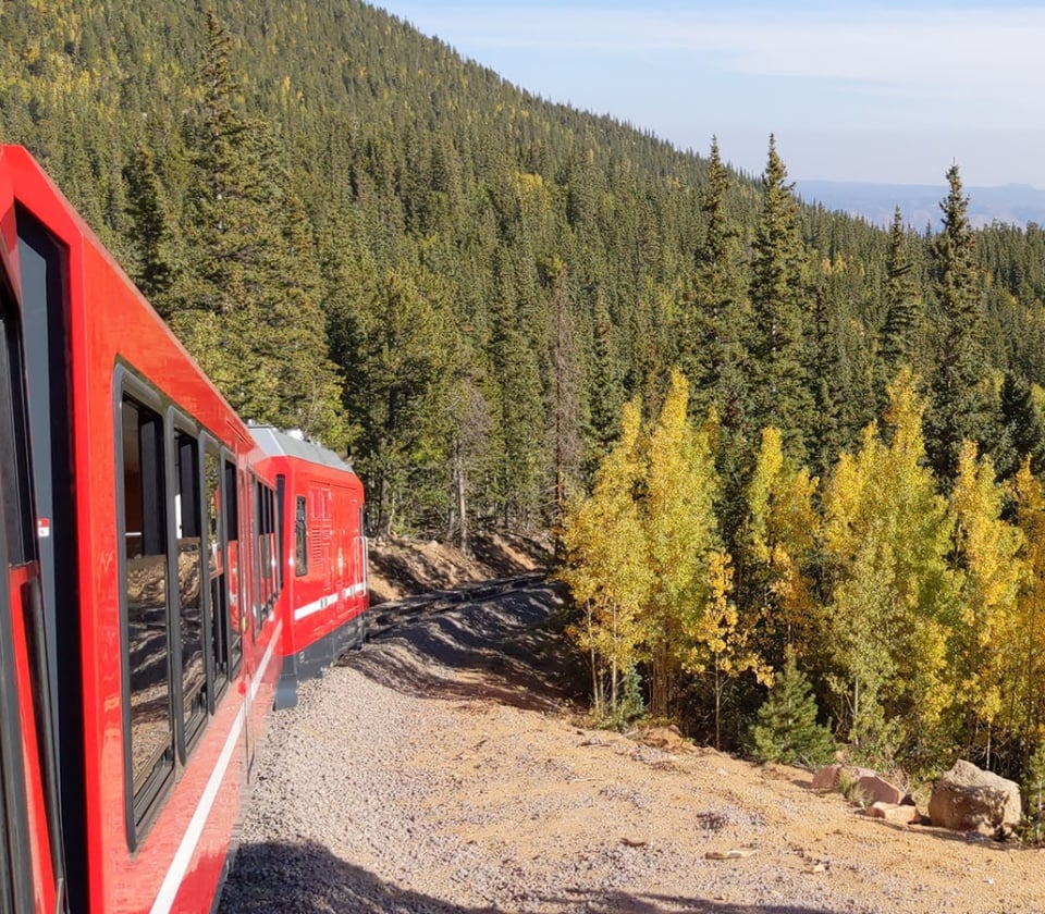 Red train on tracks with trees