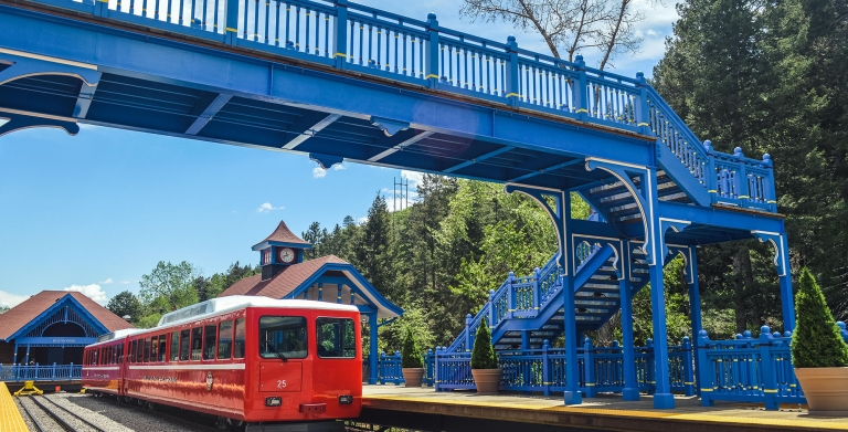 Red train on track with blue skies and green trees